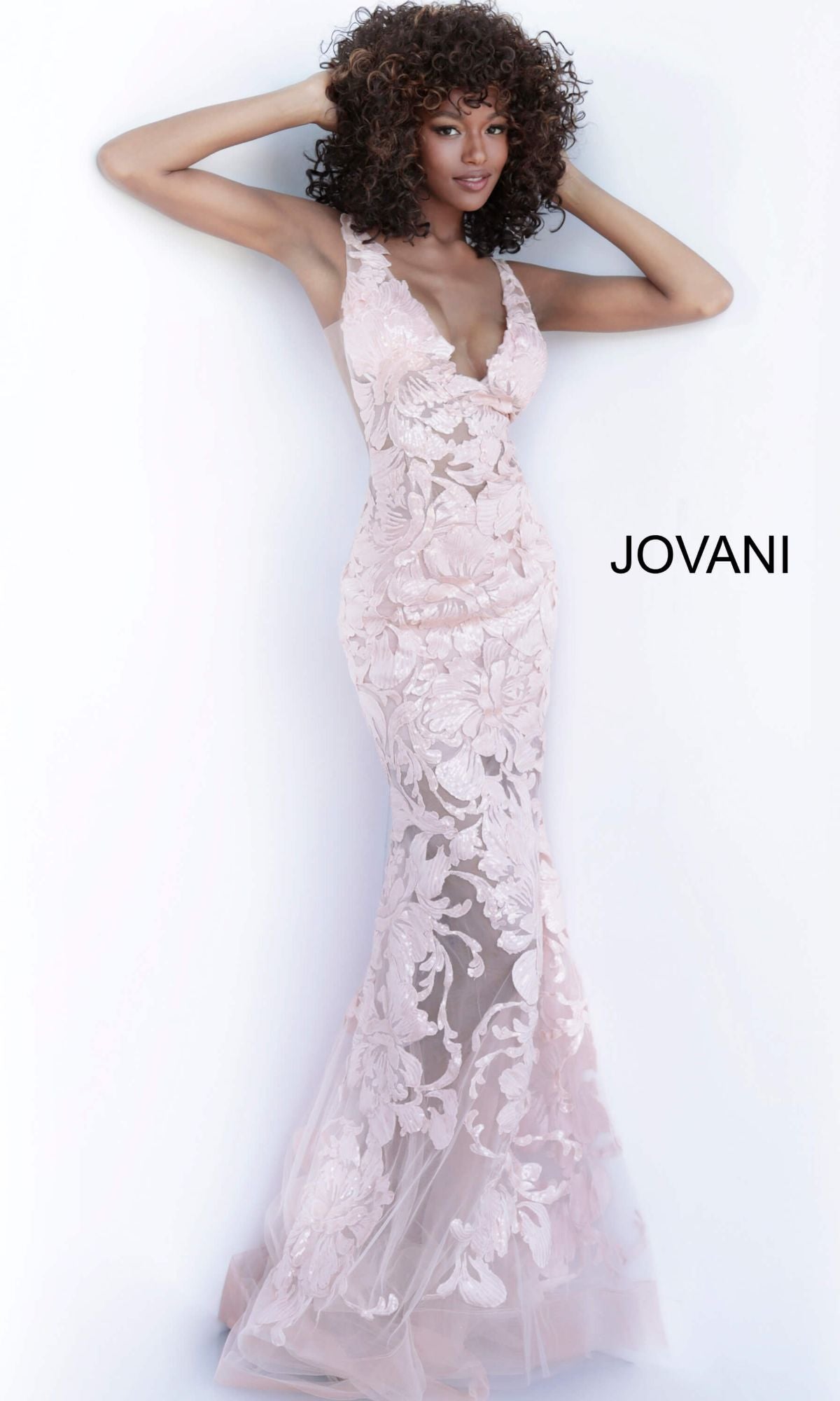 A woman poses in a sleeveless, light pink Jovani Embroidered Long Prom Dress with sequins and floral lace details. The word